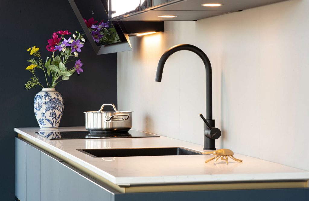 Moderne blauwe keuken met gouden greeplijsten en marmer blad bij KüchenTreff Dieren
